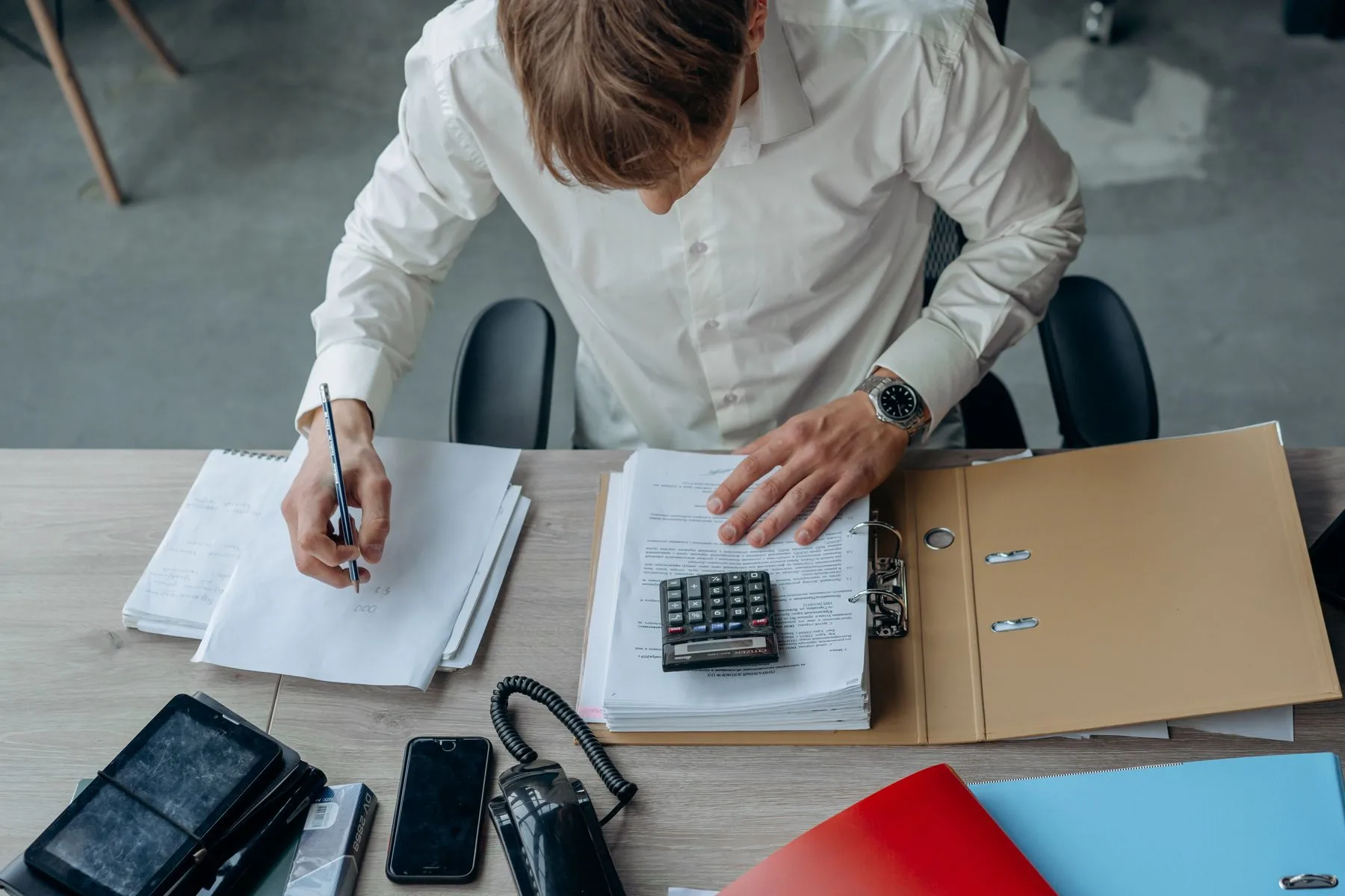 An analyst checking financial documents and recording calculations.